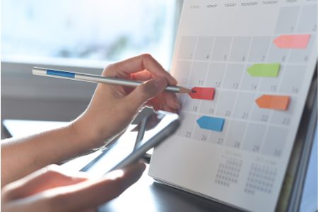 A person is looking at a calendar with sticky notes on it
