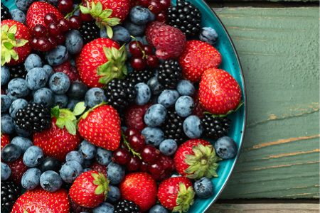 A blue plate filled with strawberries blueberries blackberries and raspberries