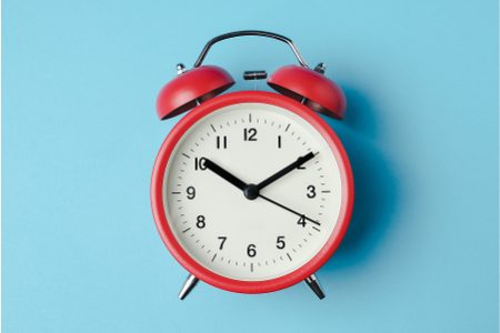 A red and white alarm clock on a blue background